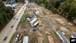 Homes and vehicles that were damaged in a flash flood from Hurricane Helene lie on the side of a road near the Swannanoa River, in Swannanoa, North Carolina, Oct. 1, 2024. 