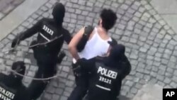 A suspect is led away by police officers after he was arrested in Berlin, Germany, April 8, 2018. He is one of six people who were detained in connection with what police and prosecutors allege was a plan to carry out an attack on Berlin's half-marathon Sunday.