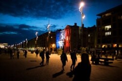 Pedestrians walk along Marseille's Old Port as the town hall is lit up in the French Tricolor to honor slain teacher Samuel Paty, Oct. 21, 2020.