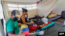 Los migrantes venezolanos se sientan dentro de las carpas instaladas en el Puente Internacional Tienditas en Cúcuta, Colombia, en la frontera con Venezuela, preparadas para los venezolanos que han estado esperando en el Puente Internacional Simón Bolívar, el 16 de junio de 2020.