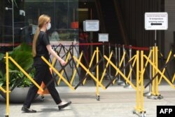 A woman wearing a face mask approaches a temperature screening area of an office building as a preventive measure against the coronavirus spread, in Singapore, March 20, 2020.