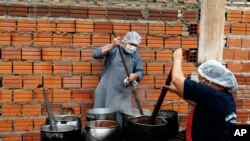 FILE - Walter Ferreira, left, and Laura Dure cook stew at a soup kitchen that feeds about 300 people daily in Luque, Paraguay, May 11, 2020.
