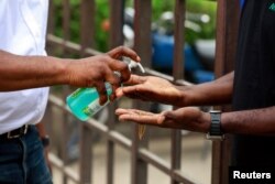 A security guard pours hand sanitising gel into a shopper's hands at the Yaba market, amid the coronavirus disease (COVID-19) outbreak, in Lagos, Nigeria, March 23, 2020.