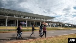 FILE - People walk in front of the Bole International Airport, in Addis Ababa, on March 17, 2020.