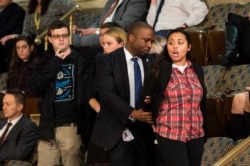 FILE - A protester is escorted out of the House Chamber during a joint session of Congress to count the Electoral College ballots in Washington, Jan. 6, 2017.