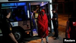 Migrants, part of a group intercepted aboard dinghies off the coast in the Mediterranean Sea, leave a bus and head toward a sports center after arriving on a rescue boat at the port of Malaga, Spain, June 23, 2018.