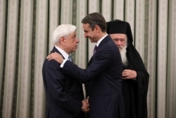 New Democracy conservative party leader Kyriakos Mitsotakis shakes hands with Greek President Prokopis Pavlopoulos, near Greece's Orthodox Church Archbishop Ieronimos, at a swearing-in ceremony as prime minister, in Athens, Greece, July 8, 2019.