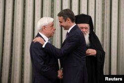 New Democracy conservative party leader Kyriakos Mitsotakis shakes hands with Greek President Prokopis Pavlopoulos, near Greece's Orthodox Church Archbishop Ieronimos, at a swearing-in ceremony as prime minister, in Athens, Greece, July 8, 2019.