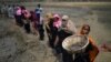 FILE - Rohingya refugee women carry baskets of dried out mud from the riverbed to help raise the ground level of their camp in preparation for monsoon season, in Shamlapur refugee camp, in Cox's Bazaar, Bangladesh, March 24, 2018.