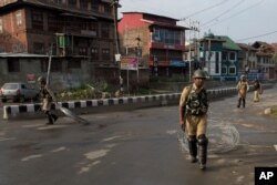 FILE -Indian Paramilitary soldiers drag barbwire as they prepare to impose curfew in Srinagar, Indian controlled Kashmir, Aug. 7, 2019.