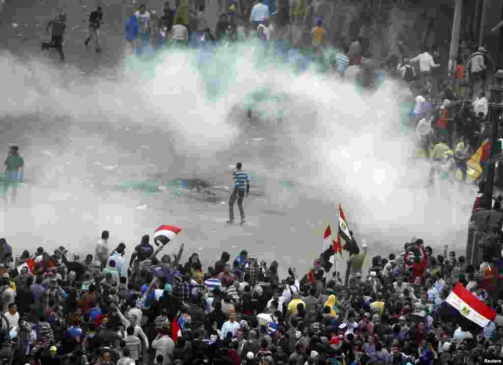 Protesters run from tear gas released by riot police during clashes at Tahrir square in Cairo November 23