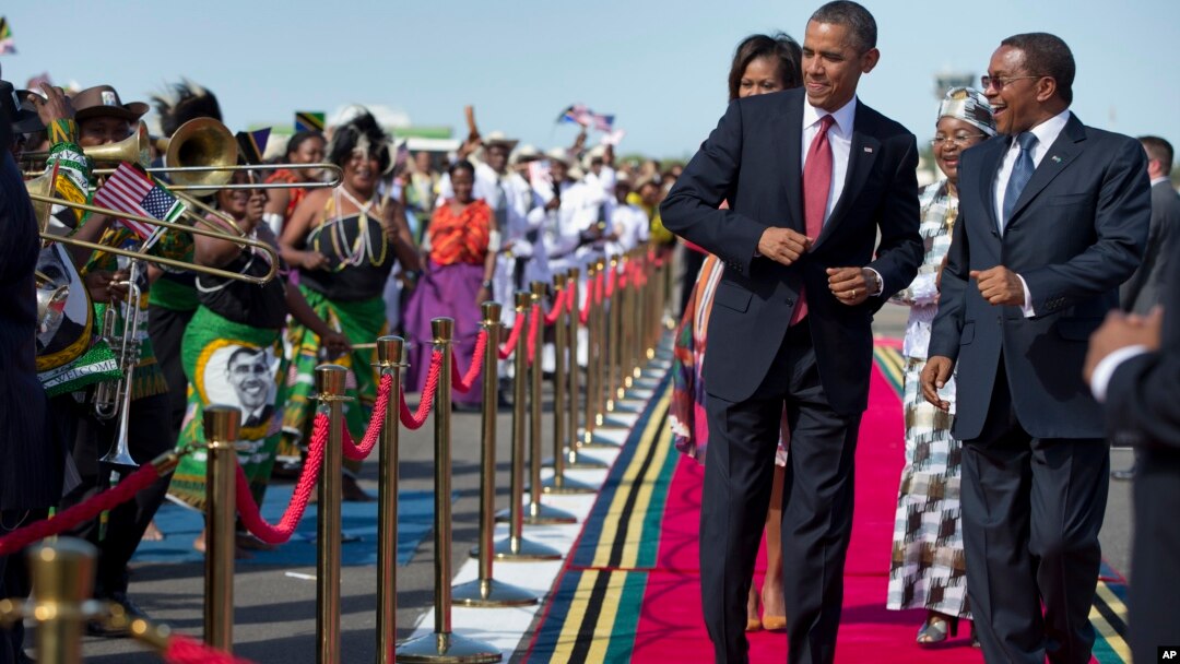 President Barack Obama, followed by first lady Michelle Obama, does a dance upon his arrival ceremony with Tanzanian President Jakaya Kikwete, right, July 1, 2013, at Julius Nyerere International Airport in Dar Es Salaam, Tanzania.