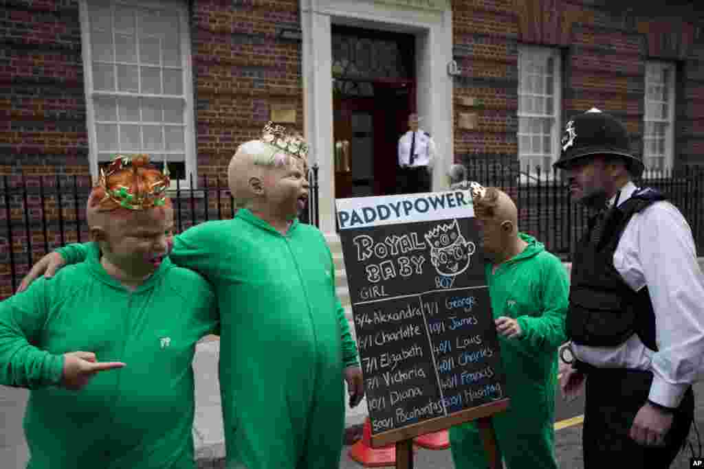 A police officer speaks to representatives from a betting company wearing baby masks and posing for the media beside a board detailing odds on different names for the royal baby as they perform a stunt outside St. Mary&#39;s Hospital Lindo Wing in London.