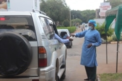 A health official disinfects people arriving at Wilkins Hospital, in Harare, May 12, 2021. (Columbus Mavhunga/VOA)