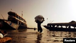 Un travailleur apporte des céréales devant être transportées en pirogue sur le fleuve Niger, à Mopti, le 7 février 2007.