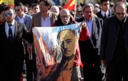 FILE - A man holds a cloth with a depiction of the late Spanish dictator Francisco Franco, during the reinterment of his remains, outside Mingorrubio's cemetery, on the outskirts of Madrid, Spain, Oct. 24, 2019.
