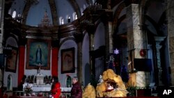 Chinese women walk past a decoration displaying a Baby Jesus doll part of a Nativity scene, at the Nantang Catholic Church in Beijing, China, Dec. 28, 2016.