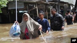 Warga berpegangan pada tali untuk melalui jalanan yang tergenang banjir di Tangerang, Banten, Kamis (2/1).