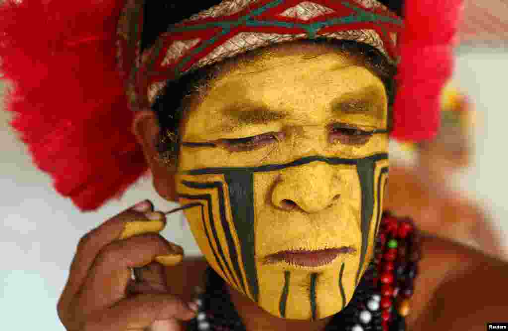 Native Brazilian Nobre Arariba paints his face in the town of Santa Cruz Cabralia, Brazil, June 24, 2014.