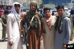 A Taliban fighter, second left, is seen with locals at Pul-e-Khumri on Aug. 11, 2021, after Taliban captured Pul-e-Khumri, the capital of Baghlan province.