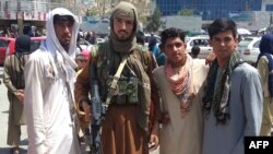 Một tay súng Taliban (thứ 2, từ trái) và người dân ở Pul-e-Khumri, thủ phủ tỉnh Baghlan, ngày 11/8/2021.
