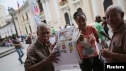 Seorang pria memegang poster yang menunjukkan surat suara di tengah kota Caracas, Venezuela, 5 Desember 2015.