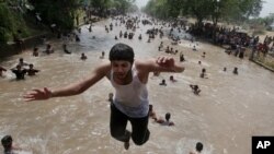 Seorang anak laki-laki melompat ke sebuah kanal di Lahore, Pakistan, di tengah gelombang panas yang mencapai 46 derajat Celsius. (Foto: Dok)