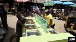 People wash their hands in basins installed by a pharmaceutical company to prevent the spread of the COVID-19 coronavirus at the Mushin Market in Lagos, March 30, 2020.