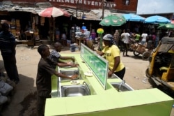 People wash their hands in basins installed by a pharmaceutical company to prevent the spread of the COVID-19 coronavirus at the Mushin Market in Lagos, March 30, 2020.