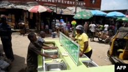 FILE - People wash their hands in basins installed by a pharmaceutical company to prevent the spread of the COVID-19 coronavirus at the Mushin Market in Lagos, Nigeria, March 30, 2020.