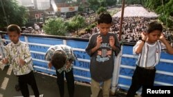 Ilustrasi. Anak-anak sedang melakukan salat di atas jembatan sementara orang dewasa menempati jalan untuk menyambut perayaan Muslim Idul Fitri. (Foto: Reuters)