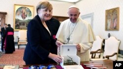 Pope Francis and German Chancellor Angela Merkel exchange gifts on the occasion of their private audience, at the Vatican, June 17, 2017. 