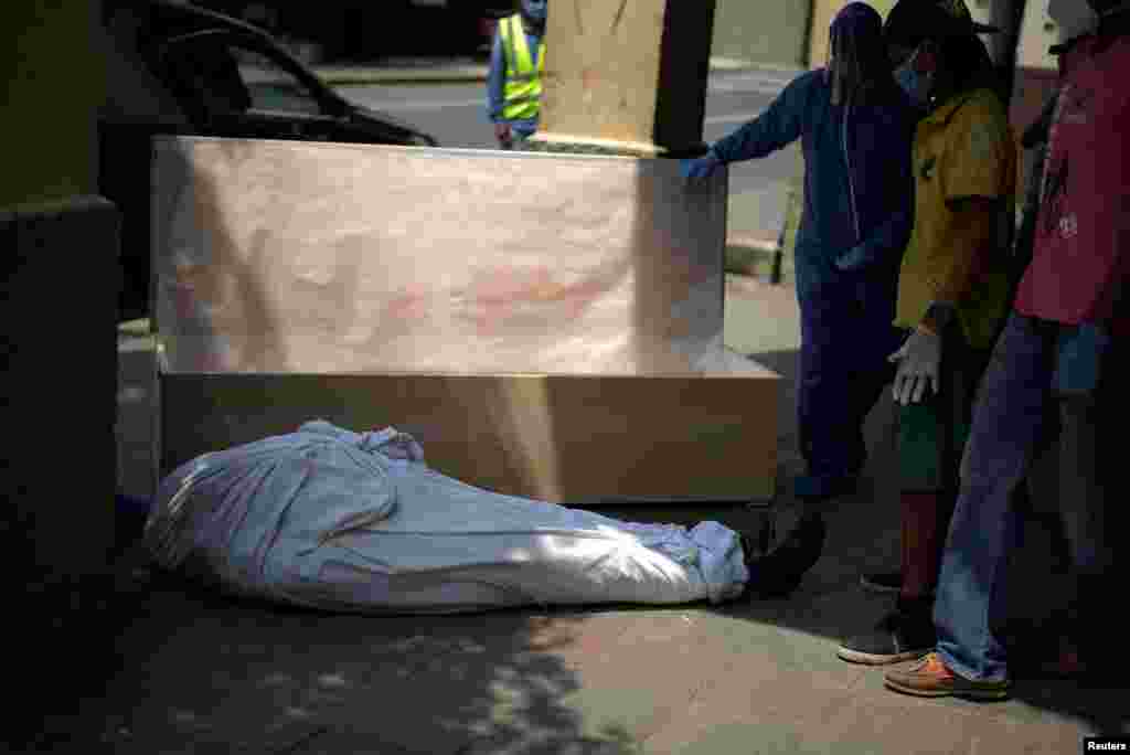 Empleados de una funeraria y familiares preparan un ata&#250;d para el cuerpo de un hombre que hab&#237;a fallecido en su casa, en medio del brote del coronavirus en Guayaquil, Ecuador.