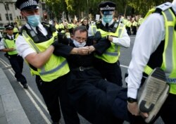 Police officers detain a priest protesting during a "peaceful disruption" of British Parliament, at Parliament Square in London, Sept. 1, 2020.