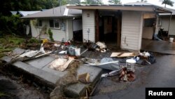 FILE - A retaining wall lies on its side after being toppled by flooding caused by Hurricane Lane in Hilo, Hawaii, Aug. 25, 2018. 