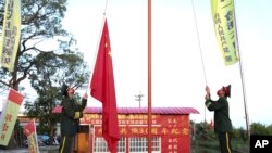 Dua pembawa bendera mengibarkan bendera China untuk memperingati Hari Nasional China daratan yang diselenggarakan oleh Partai Komunis Rakyat Taiwan di Tainan di Taiwan selatan, 1 Oktober 2022. (Foto: AP)