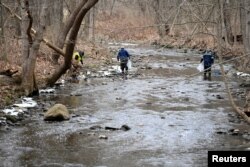 FILE: An environmental company is removing dead fish from a river that runs from the site of a train derailment in Ohio on February 6, 2023.