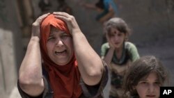 FILE - A woman screams while fleeing with her family through a destroyed alley, as Iraqi special forces continue their advance against Islamic State group militants, in the Old City of Mosul, Iraq, July 2, 2017.