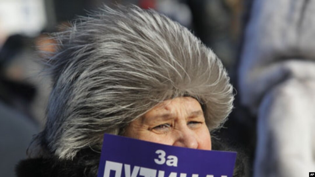 A demonstrator holds a poster reading: "For Putin!" during a rally in support of Putin's candidacy to the presidency in the March 4th election, in St.Petersburg, Russia, Saturday, Feb. 18, 2012.