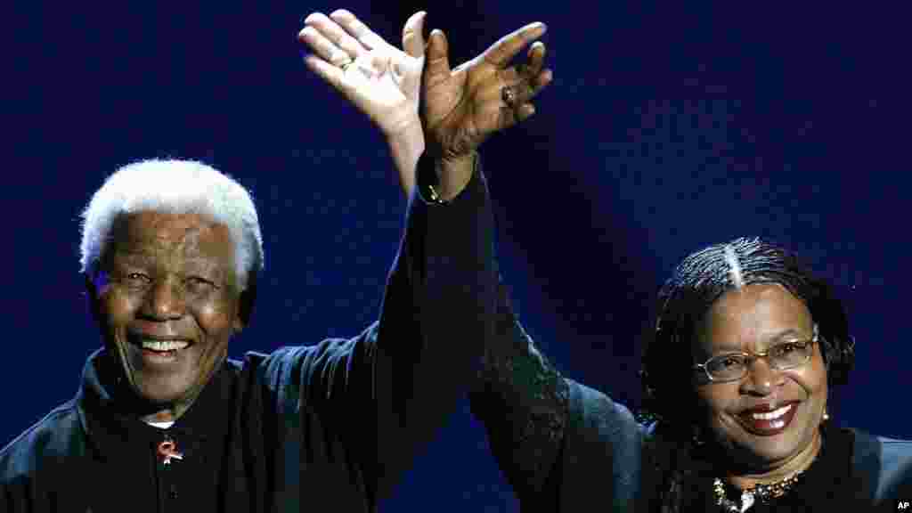 The former South African president, left, and his wife, Graca Machel, wave to the audience during a Live 8 concert in Johannesburg, South Africa, July 2, 2005. 