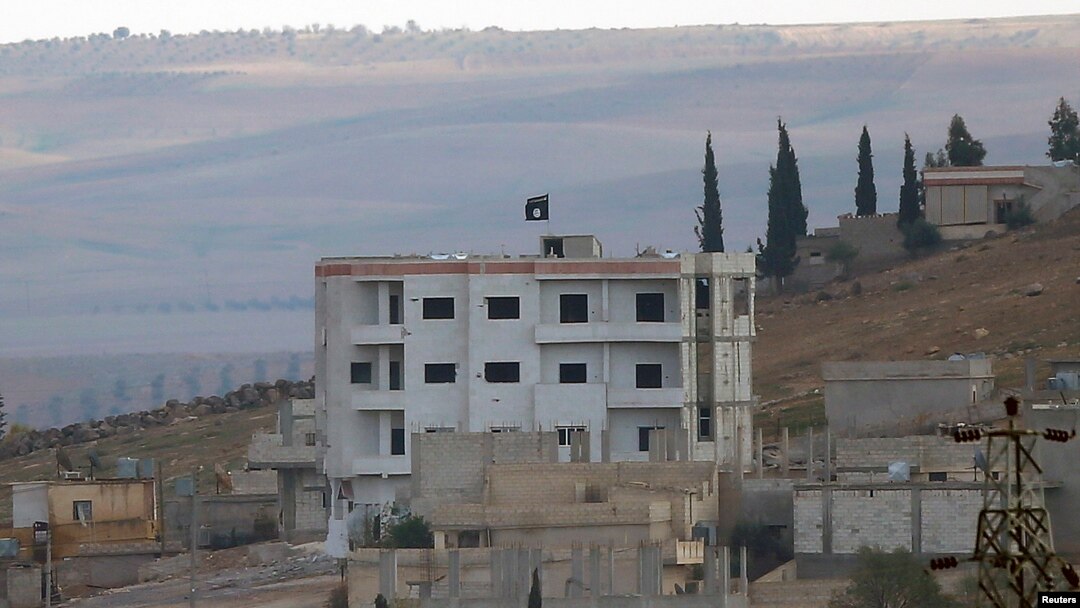 An Islamic State flag is seen atop a building in eastern Kobani, as seen from the Turkish border crossing of Mursitpinar as Kurdish Peshmerga forces fight against Islamic state fighters, Nov. 1, 2014. 