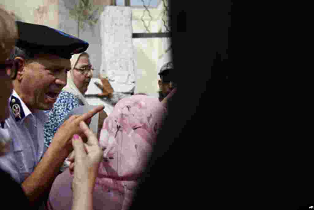 Crowds of voters overwhelm a police official at a polling station entrance. (Y. Weeks/VOA)