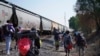 Migrantes caminan junto a un tren con dirección al norte, esperando poder subirse a él, en Huehuetoca, México, el viernes 12 de mayo de 2023. 