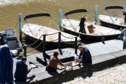 People enjoy their lunch on a sunny May 28, 2020 by the River Aura in Turku, Finland amid the novel coronavirus pandemic.