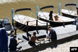 People enjoy their lunch on a sunny May 28, 2020 by the River Aura in Turku, Finland amid the novel coronavirus pandemic.