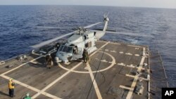 A U.S. Navy helicopter lands aboard Destroyer USS Pinckney during a crew swap before returning to a search and rescue mission for the missing Malaysian airlines flight MH370 in the Gulf of Thailand, Sunday, March 9, 2014. 