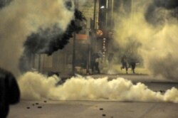 FILE - Demonstrators face police officers during clashes in Ettadhamen City near Tunis, Jan. 19, 2021.