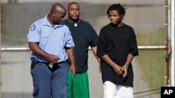 Uno de los 32 escapados (derecha) regresa a prisión tras ser devuelto por su familia.