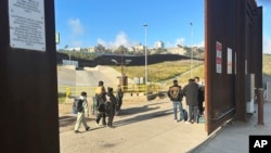ARCHIVO - Familias llegan a un campamento improvisado entre dos muros fronterizos para ser arrestadas y procesadas, el 29 de marzo de 2024, en San Diego, California, EEUU. 