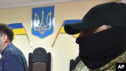 FILE - A masked police officer escorts a defendant out of a courtroom in the southern Ukrainian city of Kherson, May 17, 2018.